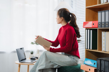 Thoughtful Pause: A woman, bathed in soft natural light, gazes out the window, lost in...