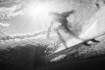 Dramatic black and white shot of a surfer inside the barrel