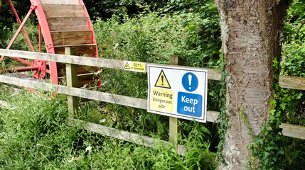warning signs by an old water wheel