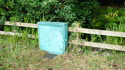 green electrical box by a wooden fence