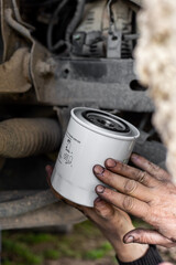Close-up of hands holding new oil filter during vehicle maintenance. Changing oil filter