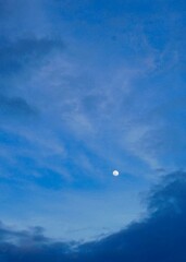 The moon in a blue and cloudy sky 