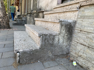 Steps, stairs, old concrete steps in front of closed entrance, staircase features rough stone texture and visible wear, creating urban street atmosphere