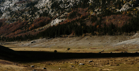 A vast autumn Ropojana valley in Montenegro Prokletije National Park stretches beneath towering...