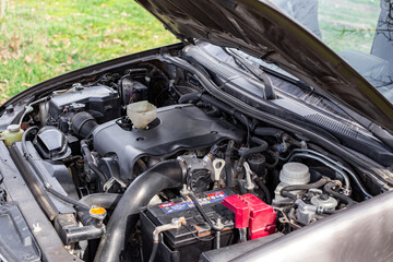 Car engine with open hood, engine components and funnel for filling engine oil
