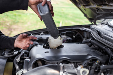 Car owner pouring fresh motor oil into engine through funnel. Changing engine oil