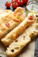 Pieces of delicious focaccia with tomatoes and oil on table, closeup