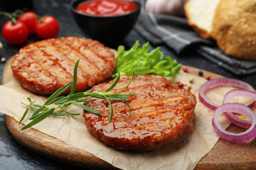 Delicious hamburger patties, tomatoes and spices on black table, closeup