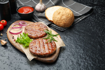 Delicious hamburger patties and spices on black table. Space for text