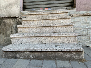 Steps, stairs, old concrete steps in front of closed entrance, staircase features rough stone texture and visible wear, creating urban street atmosphere