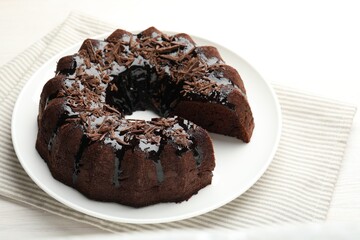 Delicious chocolate bundt cake on light wooden table, closeup