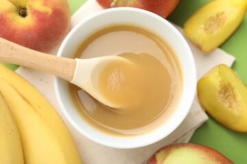 Baby food. Tasty puree in bowl and ingredients on green background, flat lay