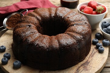 Delicious chocolate bundt cake with blueberries on wooden table, closeup