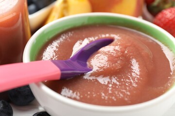Baby food. Eating tasty puree with spoon at white table, closeup