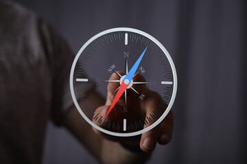 Hand pointing at a digital compass, symbolizing direction, guidance, and navigation.