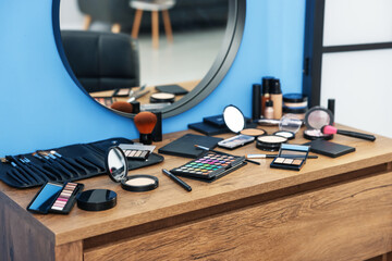 Different makeup products and brushes on vanity indoors, closeup