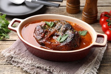 Traditional ossobuco dish with beef steak and sauce served on wooden table, closeup