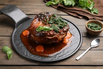 Traditional ossobuco dish with beef steak and sauce served on wooden table, closeup