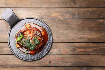 Traditional ossobuco dish with beef steak and sauce served on wooden table, top view. Space for text