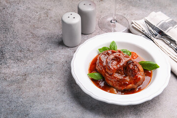 Traditional ossobuco dish with beef steak served on grey table, above view. Space for text