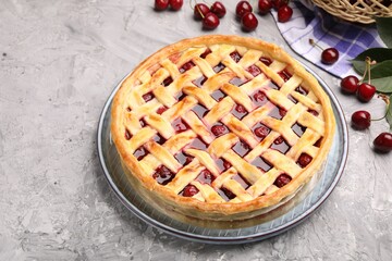Tasty cherry pie and berries on grey textured table, closeup
