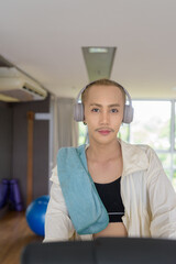 Non-binary gay man with mustache and androgynous appearance working out indoors in gym. Wearing...