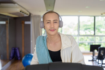 Non-binary gay man with mustache and androgynous appearance working out indoors in gym. Wearing...