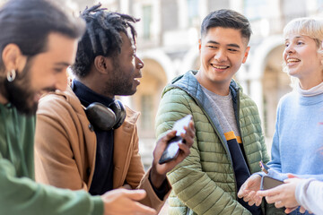 Diverse group of young adults socializing with smartphones outdoors in urban setting with joyful energy