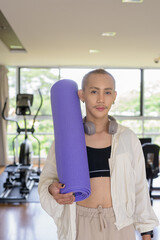 Non-binary gay man with mustache and androgynous appearance working out indoors in gym. Wearing...