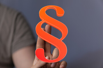 Hand holding a 3D paragraph symbol.  Legal, law, and contract concept.