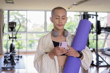 Non-binary gay man with mustache and androgynous appearance working out indoors in gym. Wearing...