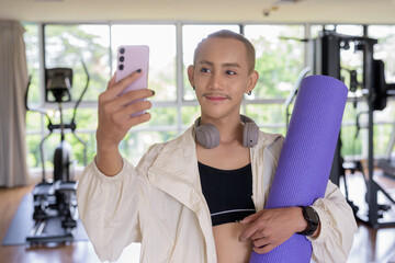 Non-binary gay man with mustache and androgynous appearance working out indoors in gym. Wearing...