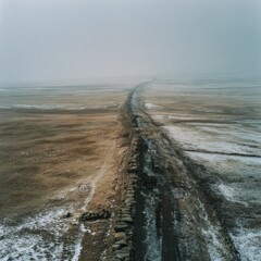 Aerial view of a stone wall stretching across a vast, muted landscape