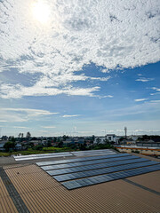 A set of solar panels installed on a rooftop under a bright, partly cloudy sky, overlooking a...
