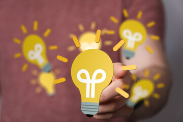 Creative ideas, innovation, and solutions concept. A hand interacts with glowing light bulbs.