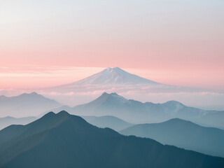 A serene landscape with layers of misty blue mountains under a soft pink and grey sky, featuring a majestic snow-capped peak in the distance.