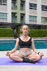 Genderfluid individual with mustache and lipstick relaxing poolside while wearing a bikini-style...