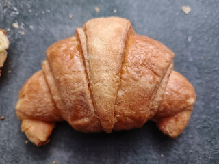 Golden croissant on a dark stone surface, crisp and flaky.