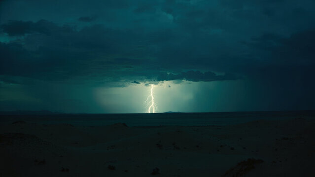 Dramatic lightning strike over a dark landscape with a stormy sky and silhouetted dunes at dusk
