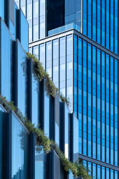 Urban architectural detail with vivid orange metallic panels, geometric perforations and crisp lines creating bold graphic composition under clear daylight in contemporary city architecture.