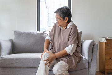Arthritis is a chronic disease problem in elderly healthcare, Asian old female touching her leg...
