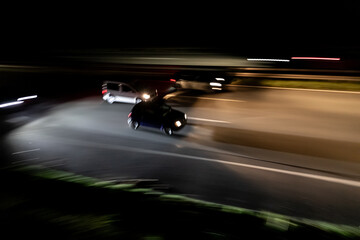 Fototapeta premium Night photography of blurred cars speeding on highway with headlights 