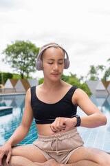 Genderfluid individual with mustache and lipstick relaxing poolside while wearing a bikini-style...