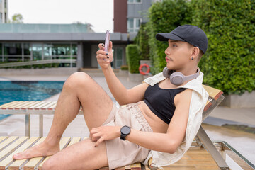 Genderfluid individual with mustache and lipstick relaxing poolside while wearing a bikini-style...