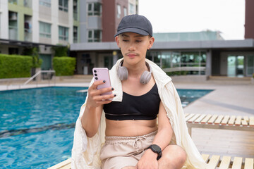 Genderfluid gay man with mustache and lipstick relaxing poolside while wearing a bikini-style top....