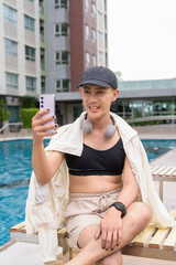 Genderfluid gay man with mustache and lipstick relaxing poolside while wearing a bikini-style top....