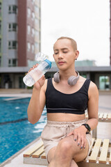 Genderfluid gay man with mustache and lipstick relaxing poolside while wearing a bikini-style top....