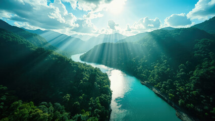 Aerial view of a river winding through lush green mountains under a bright sun with dramatic light rays and blue sky