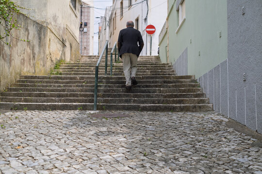 Elderly Man Walking up Narrow Portuguese Streets  - Powered by Adobe
