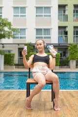 Genderfluid individual with mustache and lipstick relaxing poolside while wearing a bikini-style...